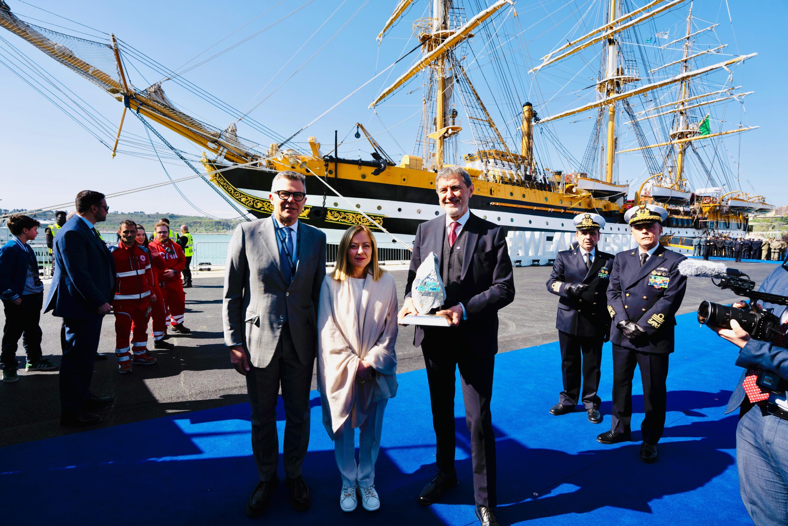 Il Presidente del Consiglio Giorgia Meloni, Marco Marsilio, Presidente della Regione Abruzzo, e Paolo Bellino, Direttore Generale e Amministratore Delegato RCS Sports & Events, davanti all'Amerigo Vespucci con il trofeo de Il Giro d'Abruzzo.